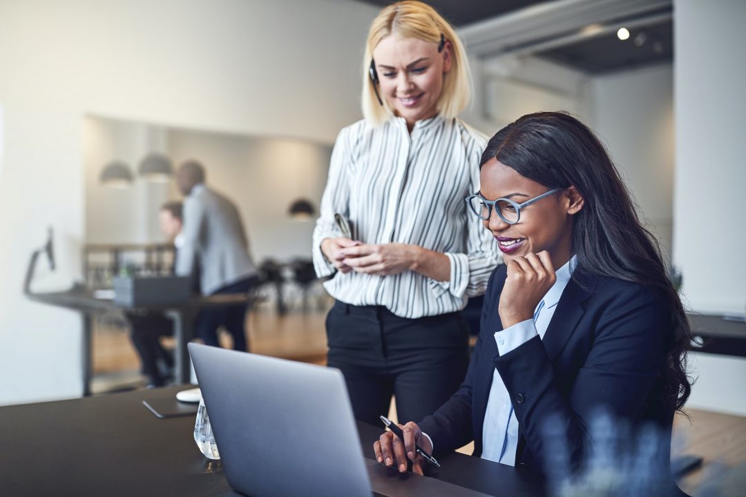 smiling businesswomen working over a laptop together in an office